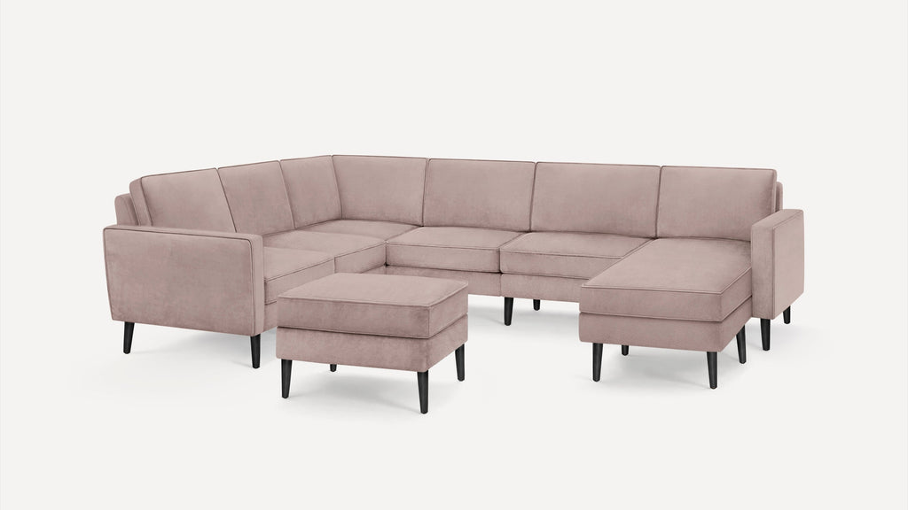 Light pink upholstered sectional sofa with clean lines and black tapered wooden legs, including a matching ottoman.