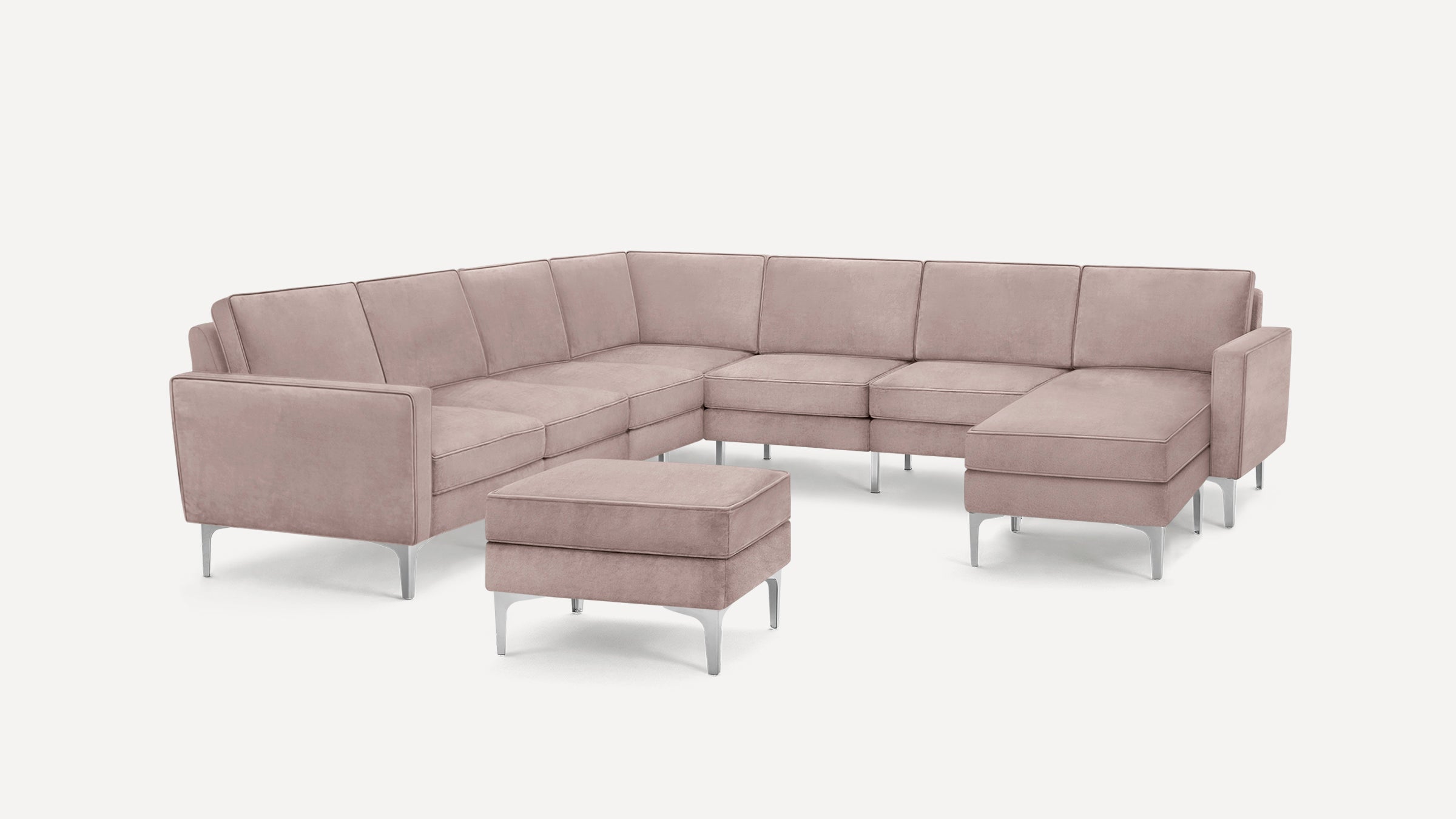 Blush pink modern sectional sofa with metal legs, including a matching ottoman, set against a plain white background.