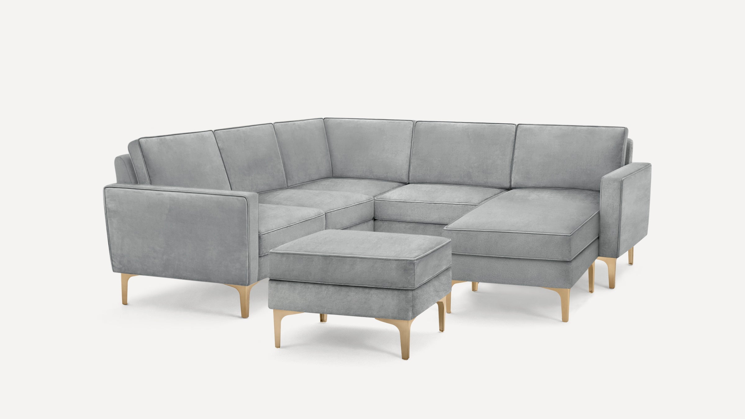Modern gray sectional sofa with chaise lounge and matching ottoman, featuring gold metal legs and clean lines.