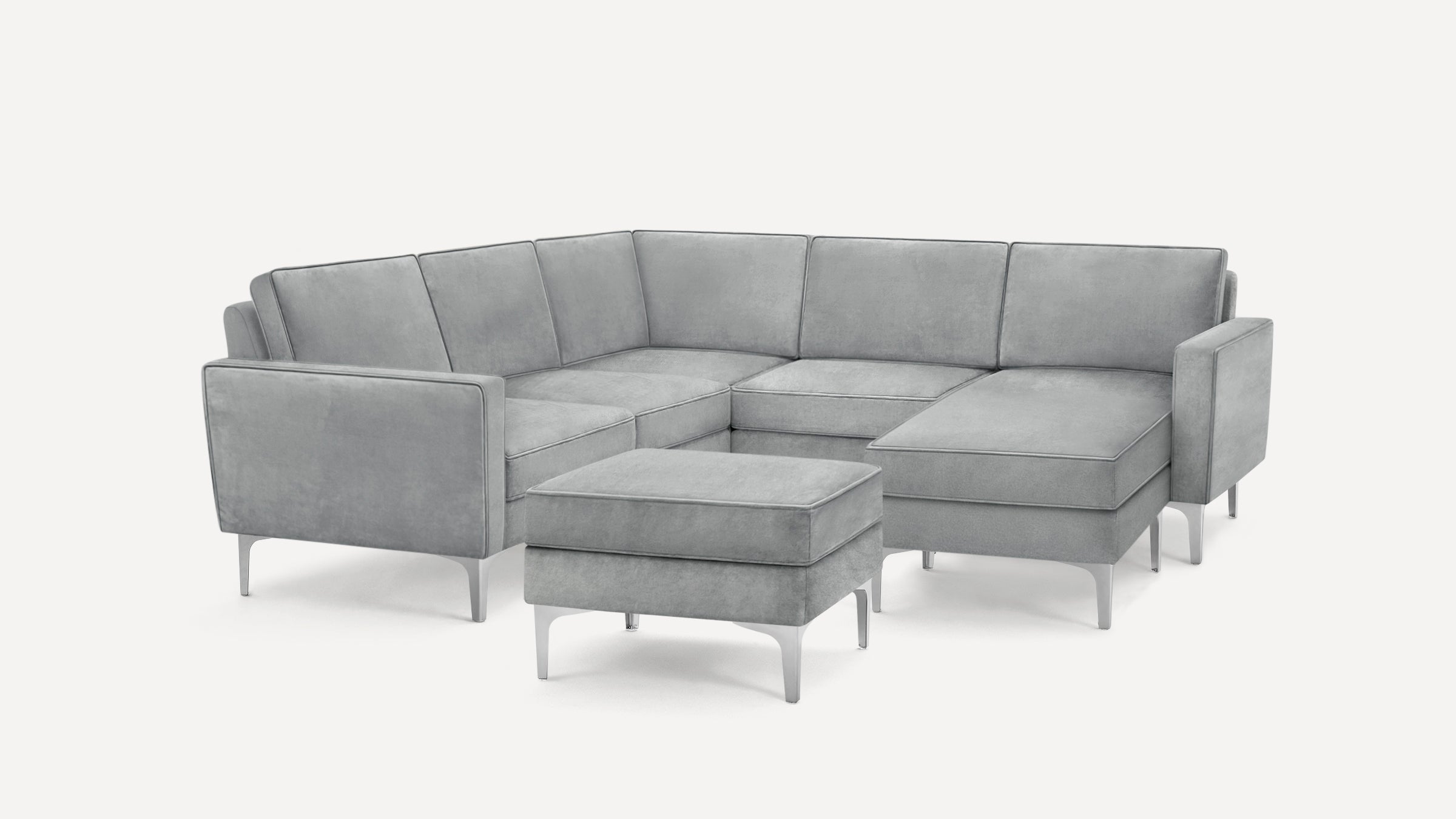 Modern light gray sectional sofa with chaise and matching ottoman, featuring sleek metal legs and soft fabric upholstery.