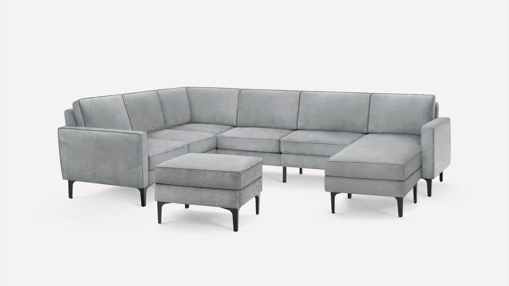 Modern light gray upholstered sectional sofa with chaise lounge and matching ottoman, featuring black tapered legs.