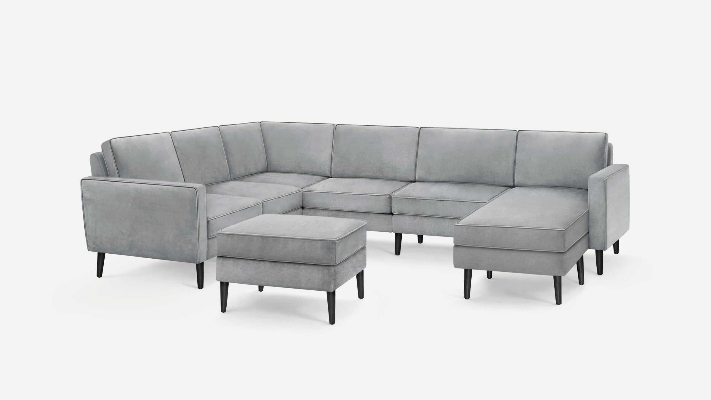 Modern light gray sectional sofa with clean lines and black tapered wooden legs, accompanied by a matching ottoman.