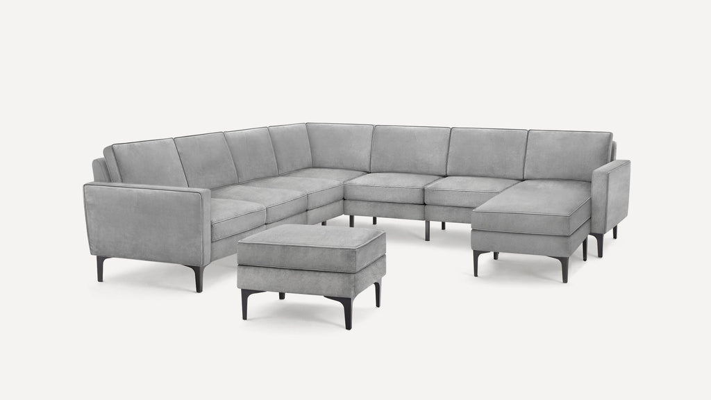 Modern L-shaped gray sectional sofa with clean lines, high metal legs, and a matching ottoman on a plain white background.