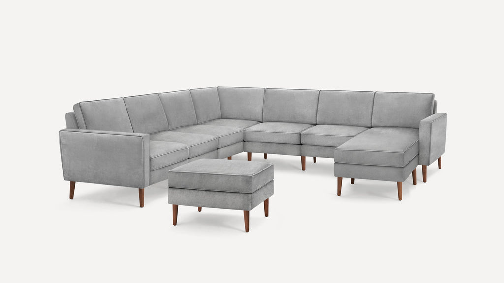Light gray sectional sofa with wooden legs and matching ottoman, featuring a modern minimalist design.