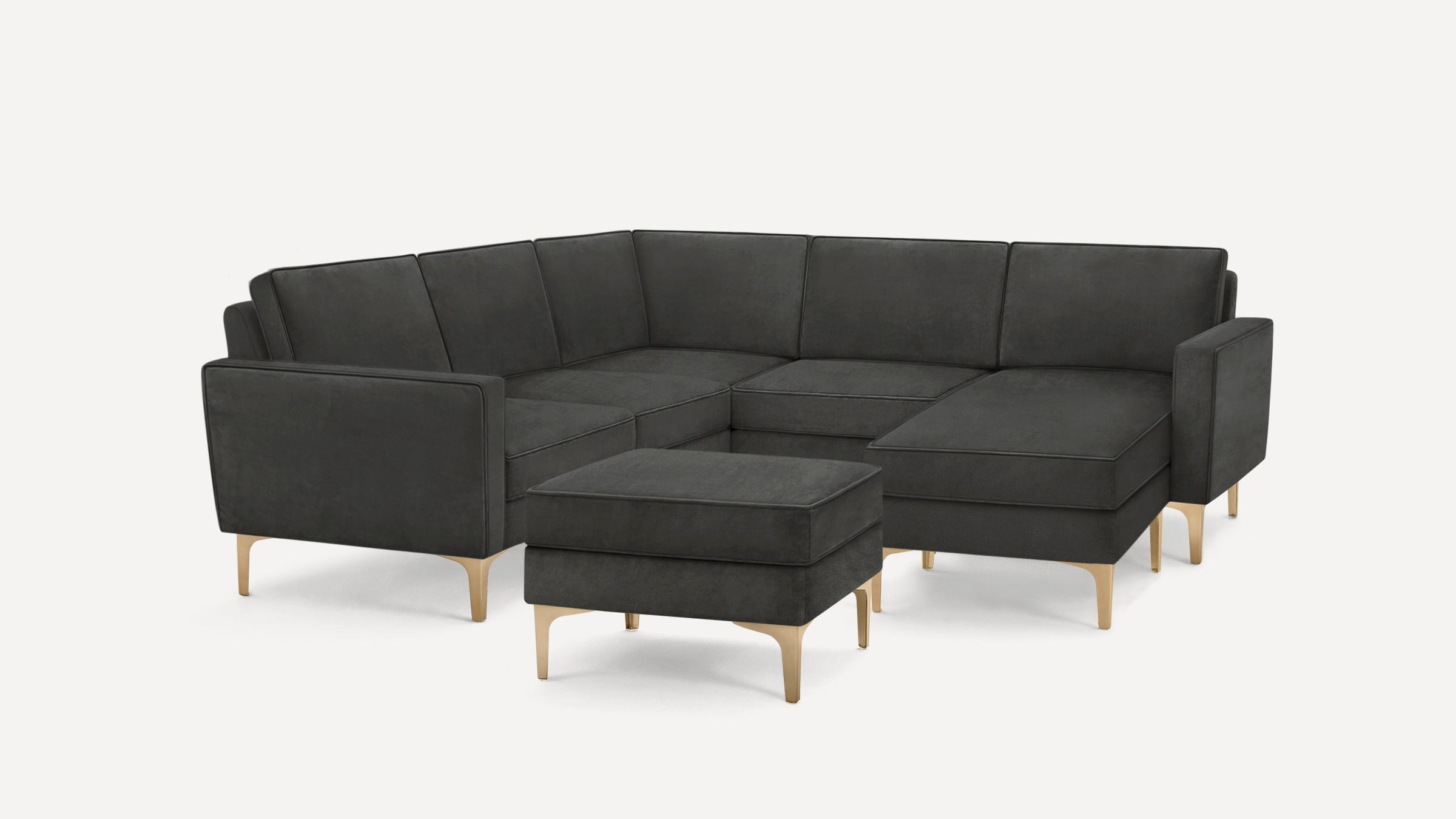 Modern dark gray sectional sofa with matching ottoman, featuring clean lines and light wooden legs on white background.
