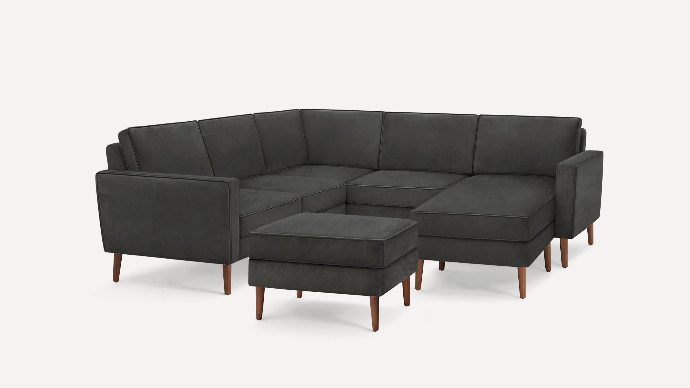 Dark gray modern sectional sofa with clean lines, wooden legs, and a matching ottoman on a white background.