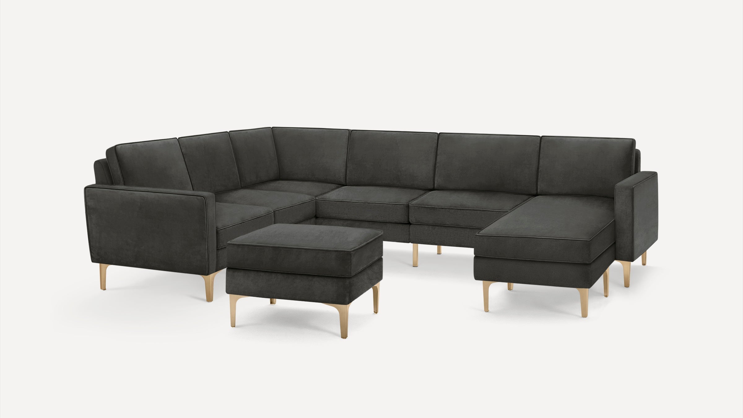 Dark gray L-shaped sectional sofa with matching ottoman and light wooden legs on white background.