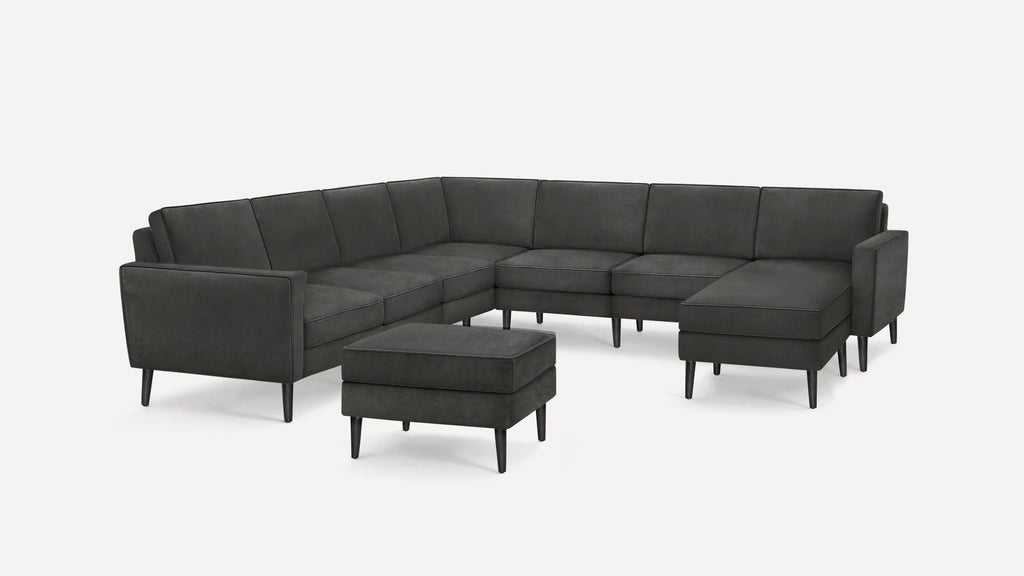Modern dark gray fabric sectional sofa with a matching ottoman, featuring clean lines and black tapered legs.