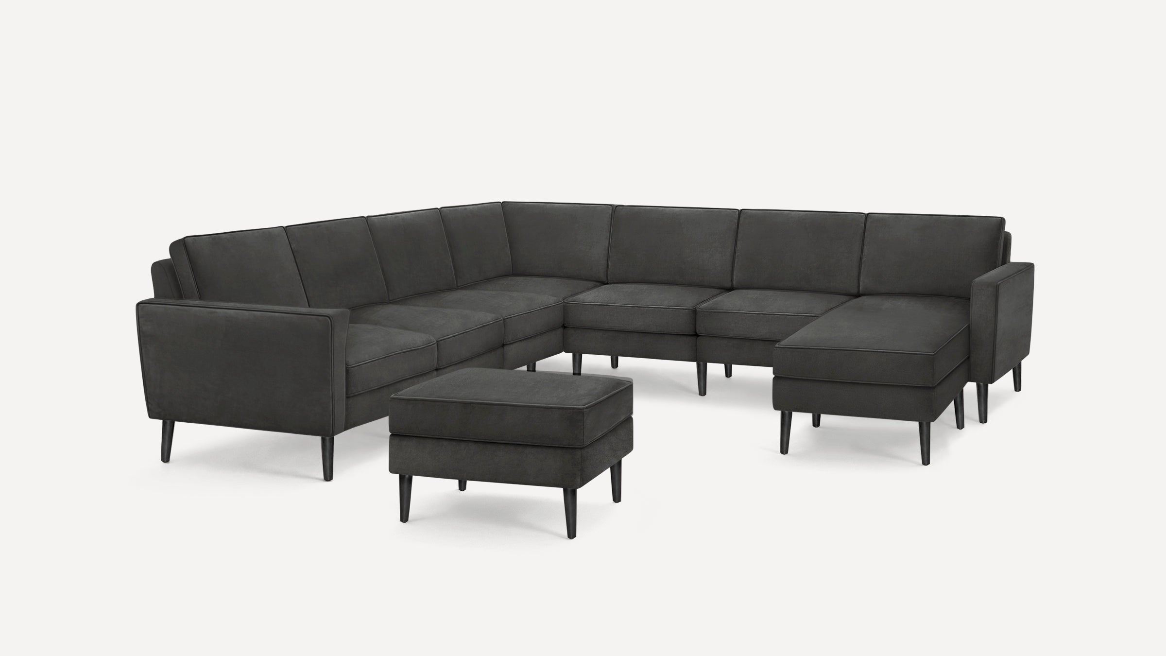 Modern dark gray fabric sectional sofa with a matching ottoman, featuring clean lines and black tapered legs.