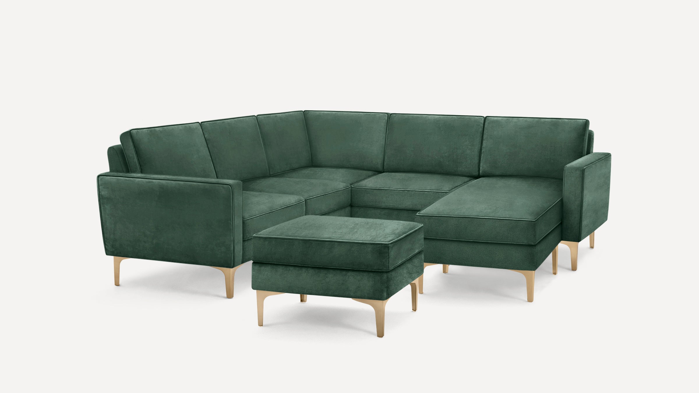 Modern green velvet sectional sofa with clean lines, plush cushions, and light wooden legs, featuring a matching ottoman.