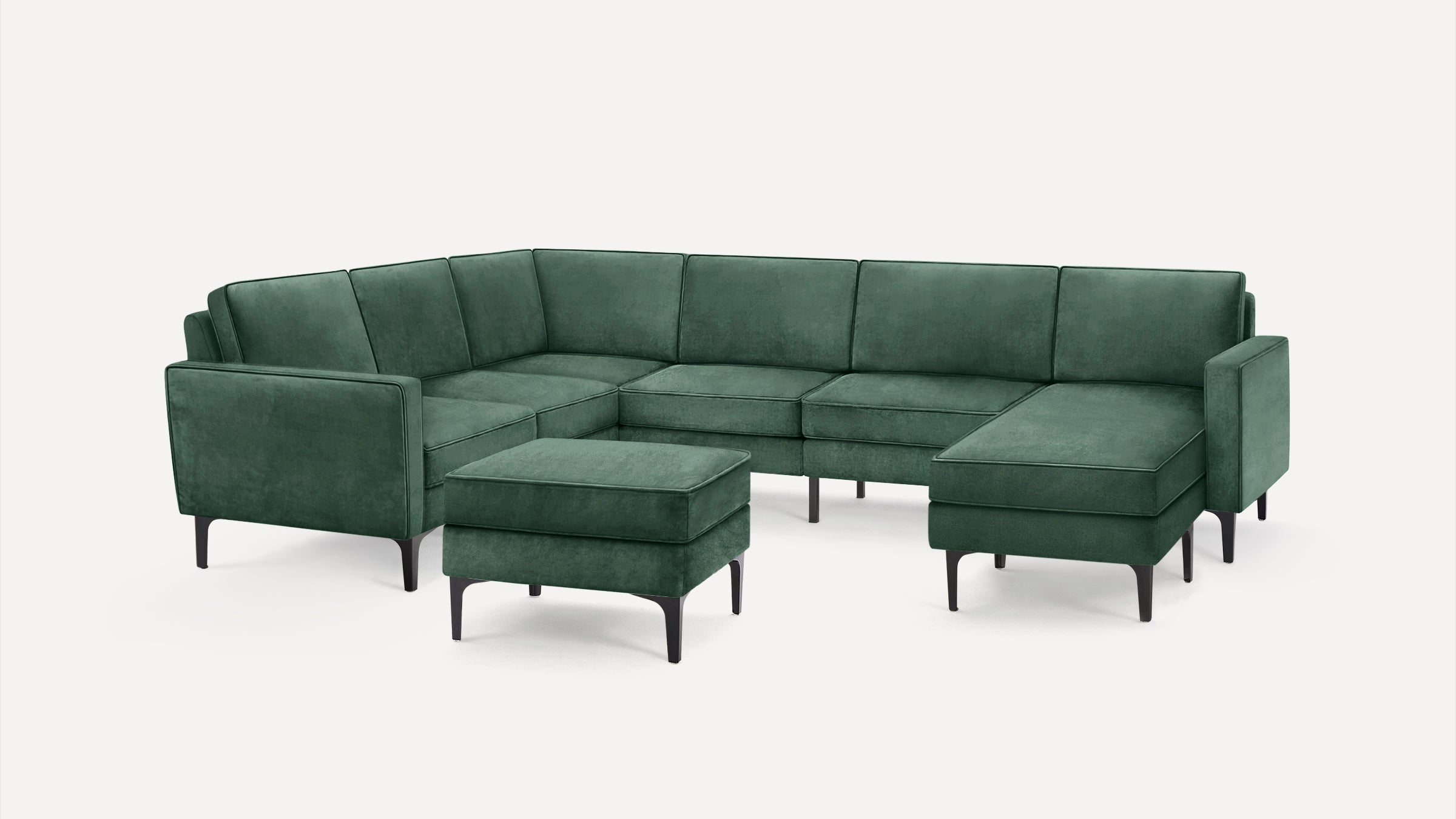 Dark green velvet sectional sofa with clean lines, thin black legs, and matching ottoman on white background.