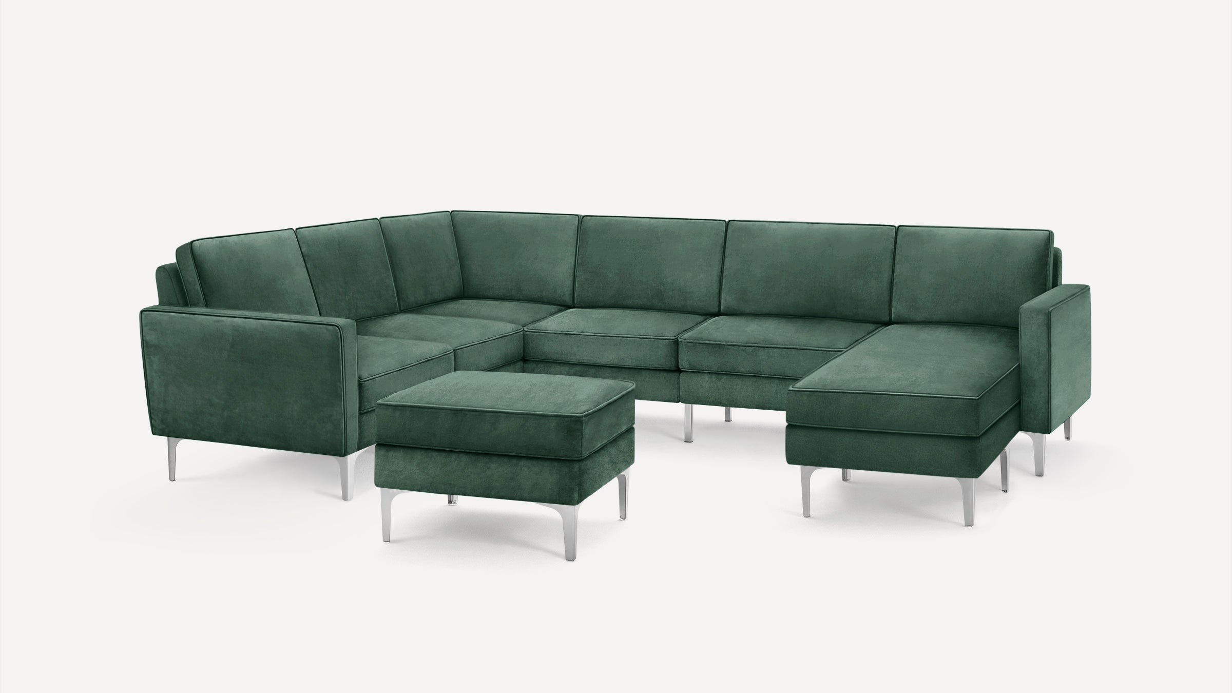 Modern green velvet sectional sofa with metal legs and matching ottoman on a white background.