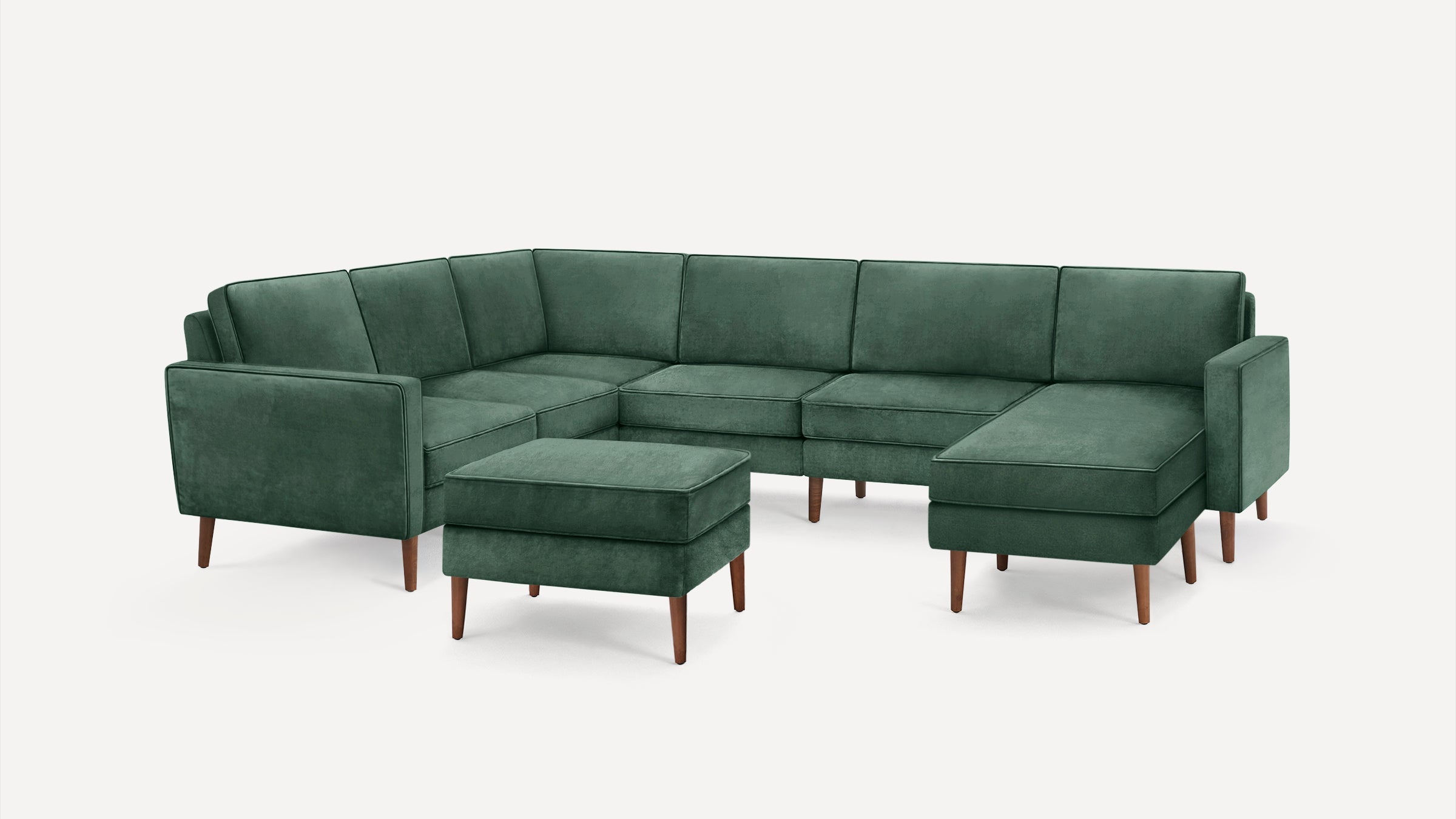 Green velvet L-shaped sectional sofa with matching ottoman and wooden legs, featuring clean lines and modern design.