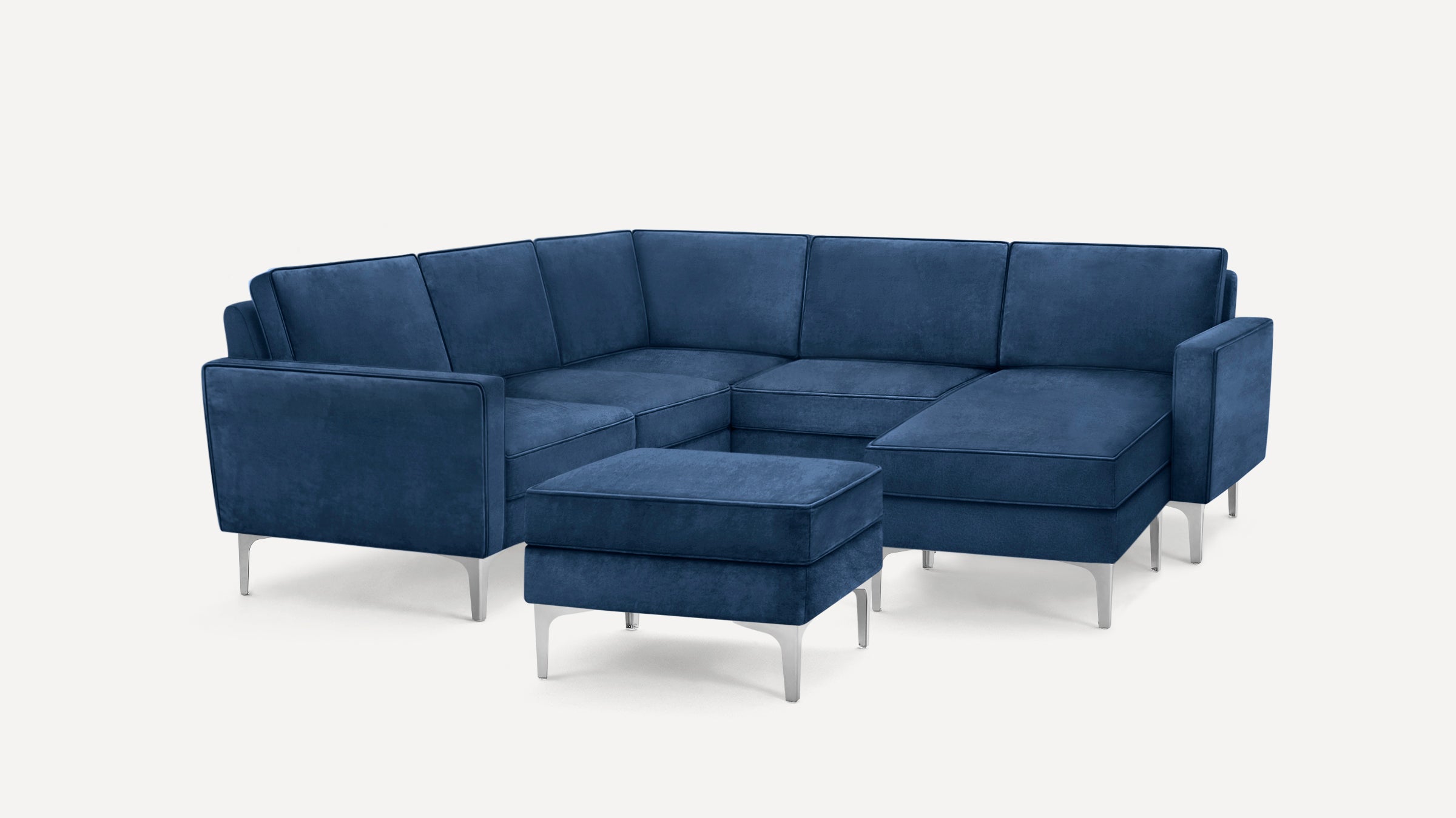 Modern navy blue sectional sofa with metal legs and matching ottoman on a white background.