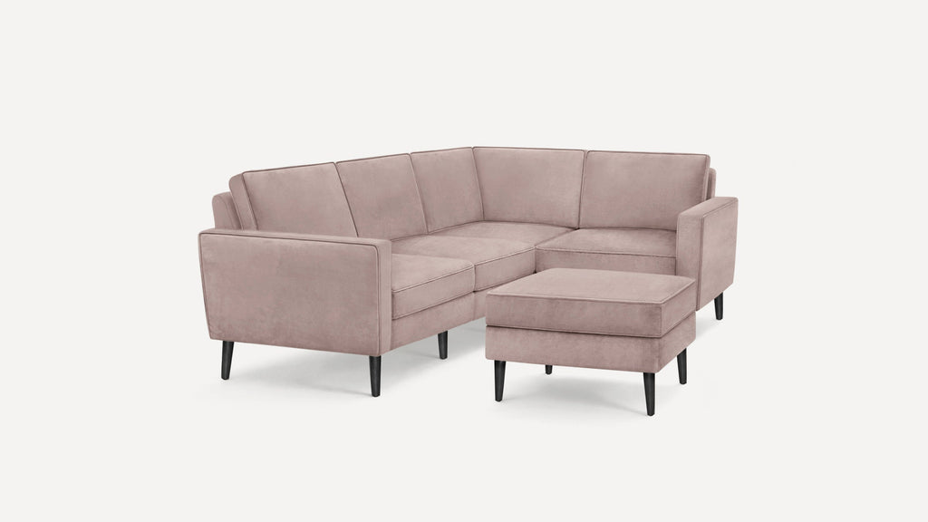 Light mauve velvet L-shaped sectional sofa with black tapered legs and matching ottoman, modern minimalist design.