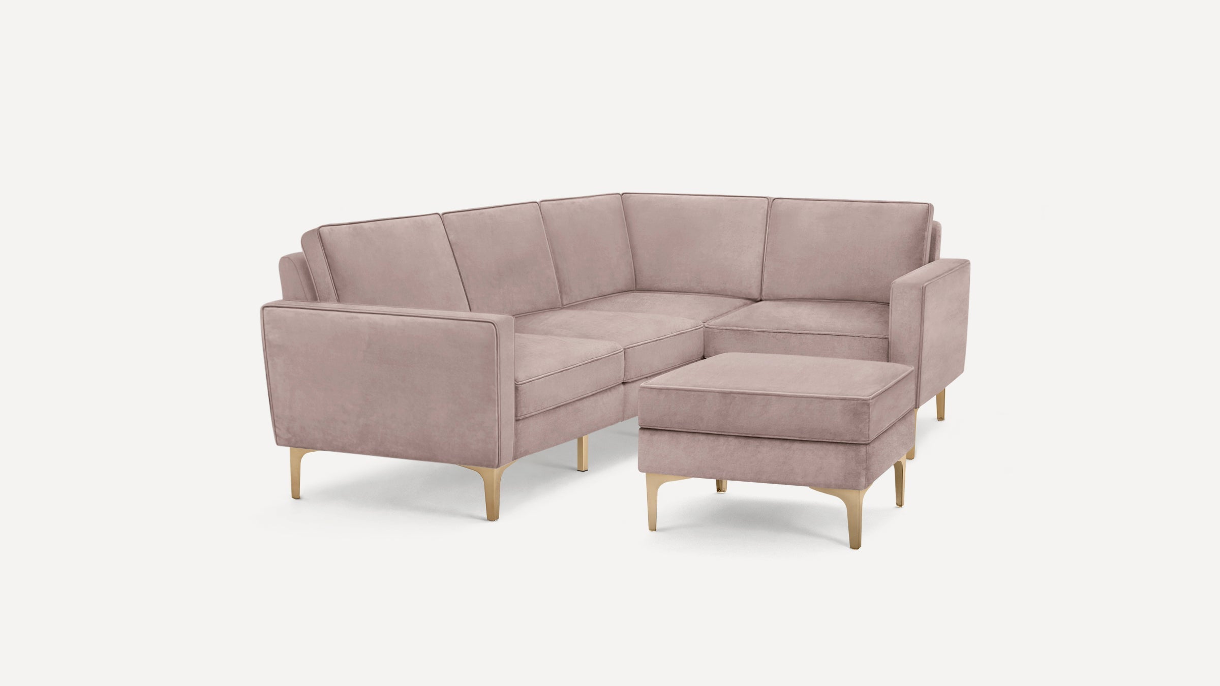 Modern light mauve velvet sectional sofa with clean lines, cushioned seats, and matching ottoman on gold tapered legs.