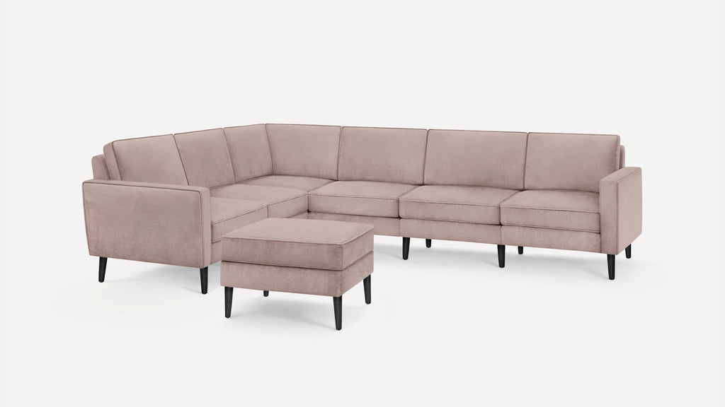 Modern L-shaped sectional sofa with soft pink upholstery and black tapered legs, accompanied by a matching square ottoman.