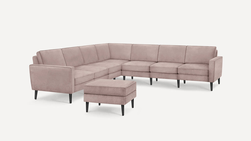 Light pink modern sectional sofa with clean lines, black tapered legs, and a matching cushioned ottoman.