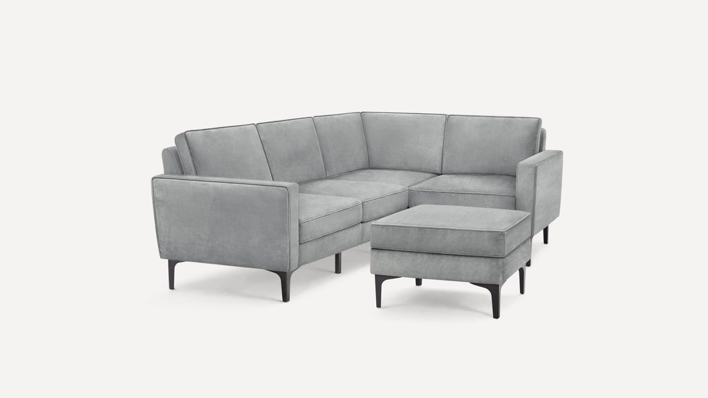 Modern light gray velvet L-shaped sectional sofa with sleek black legs and matching rectangular ottoman.