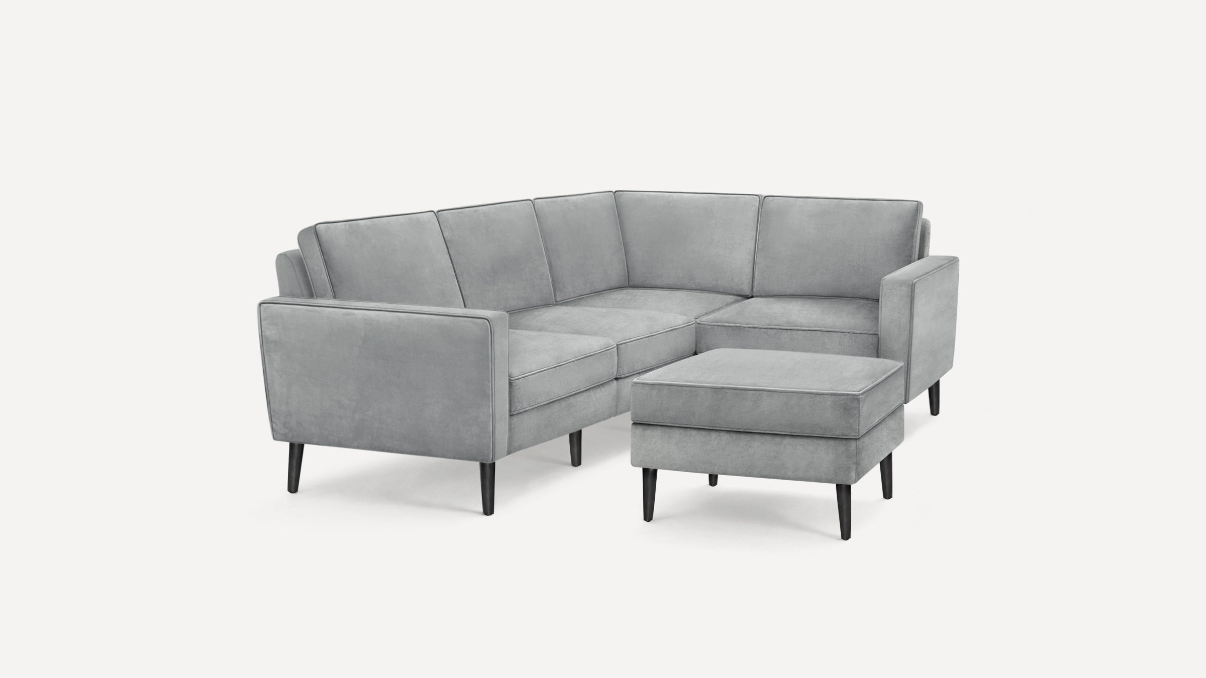 Light gray modern L-shaped sectional sofa with black tapered wooden legs and a matching ottoman.