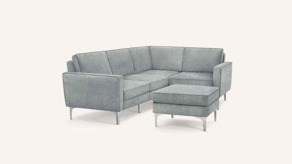 Modern gray velvet sectional sofa with clean lines, metal legs, and a matching ottoman against a white background.