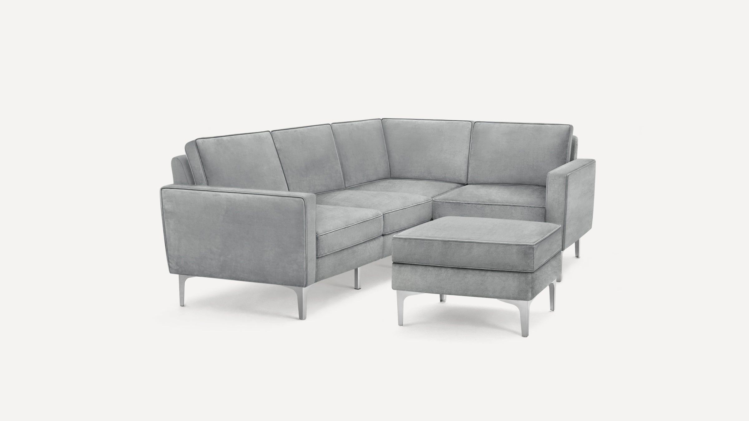 Modern gray velvet sectional sofa with clean lines, metal legs, and a matching ottoman against a white background.