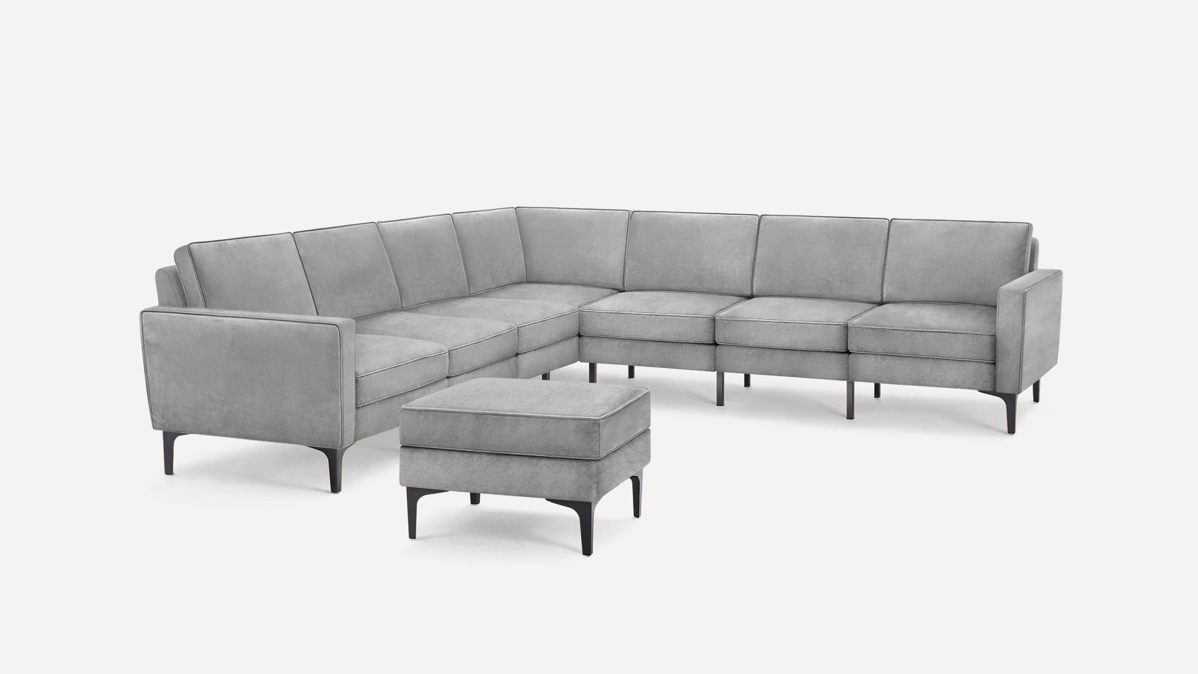Modern gray L-shaped sectional sofa with matching cushioned ottoman, square armrests, and black tapered legs on a white background.