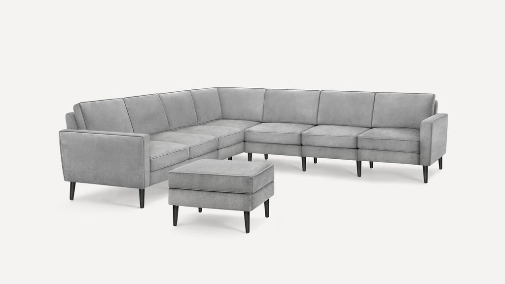 Modern gray L-shaped sectional sofa with black tapered legs, tufted cushions, and matching upholstered ottoman.