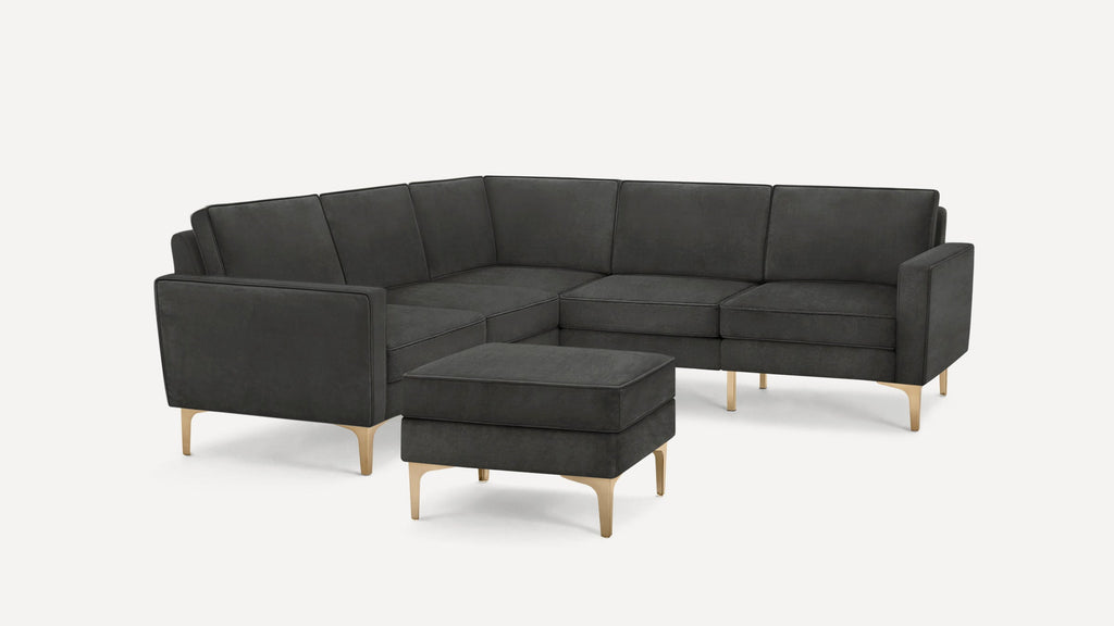 Dark gray sectional sofa with clean lines and brass-toned angled legs, accompanied by a matching ottoman.