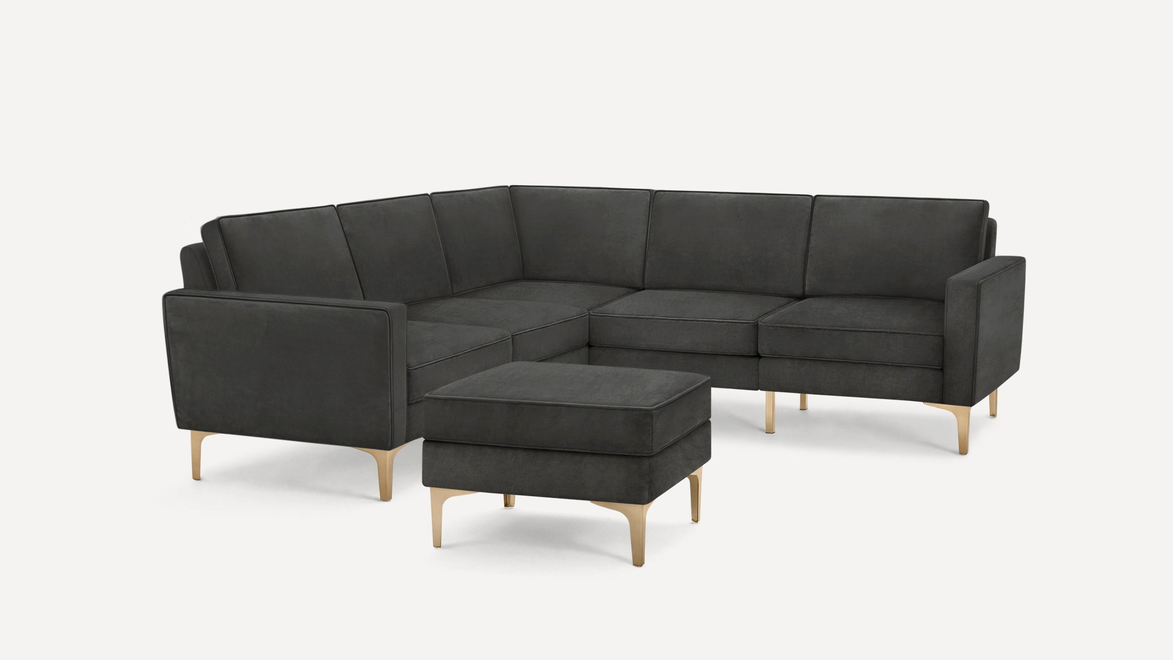 Dark gray sectional sofa with clean lines and brass-toned angled legs, accompanied by a matching ottoman.