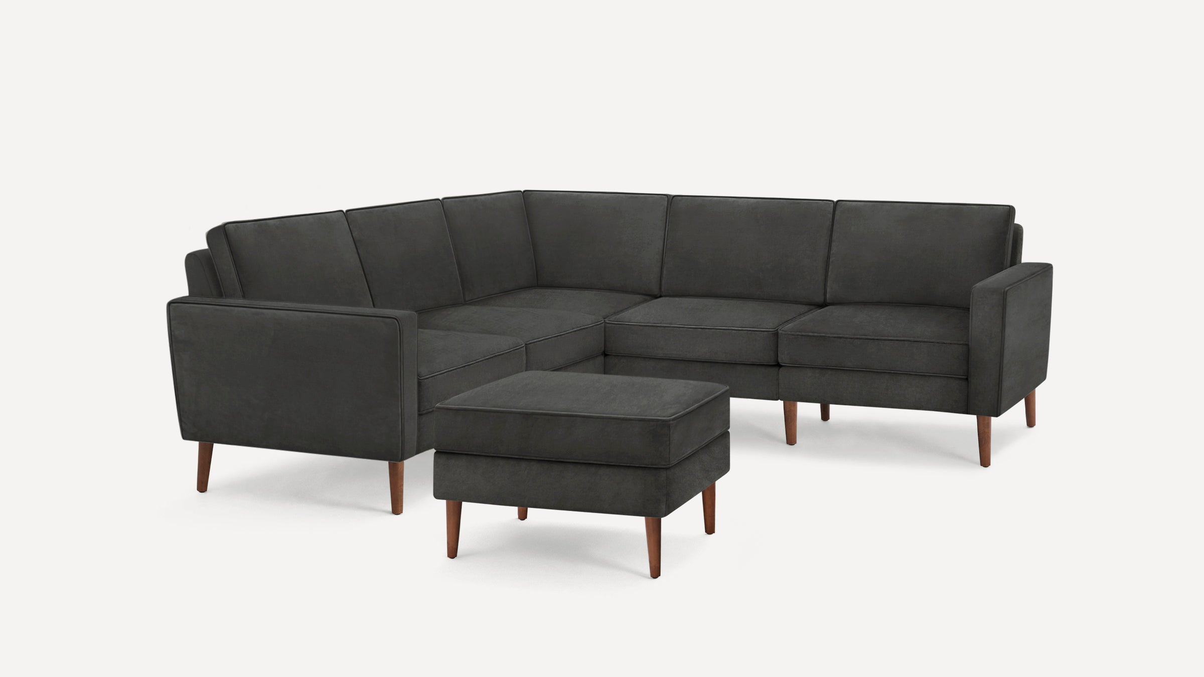 Dark gray L-shaped sectional sofa with wooden legs and matching ottoman, featuring clean lines and modern design.