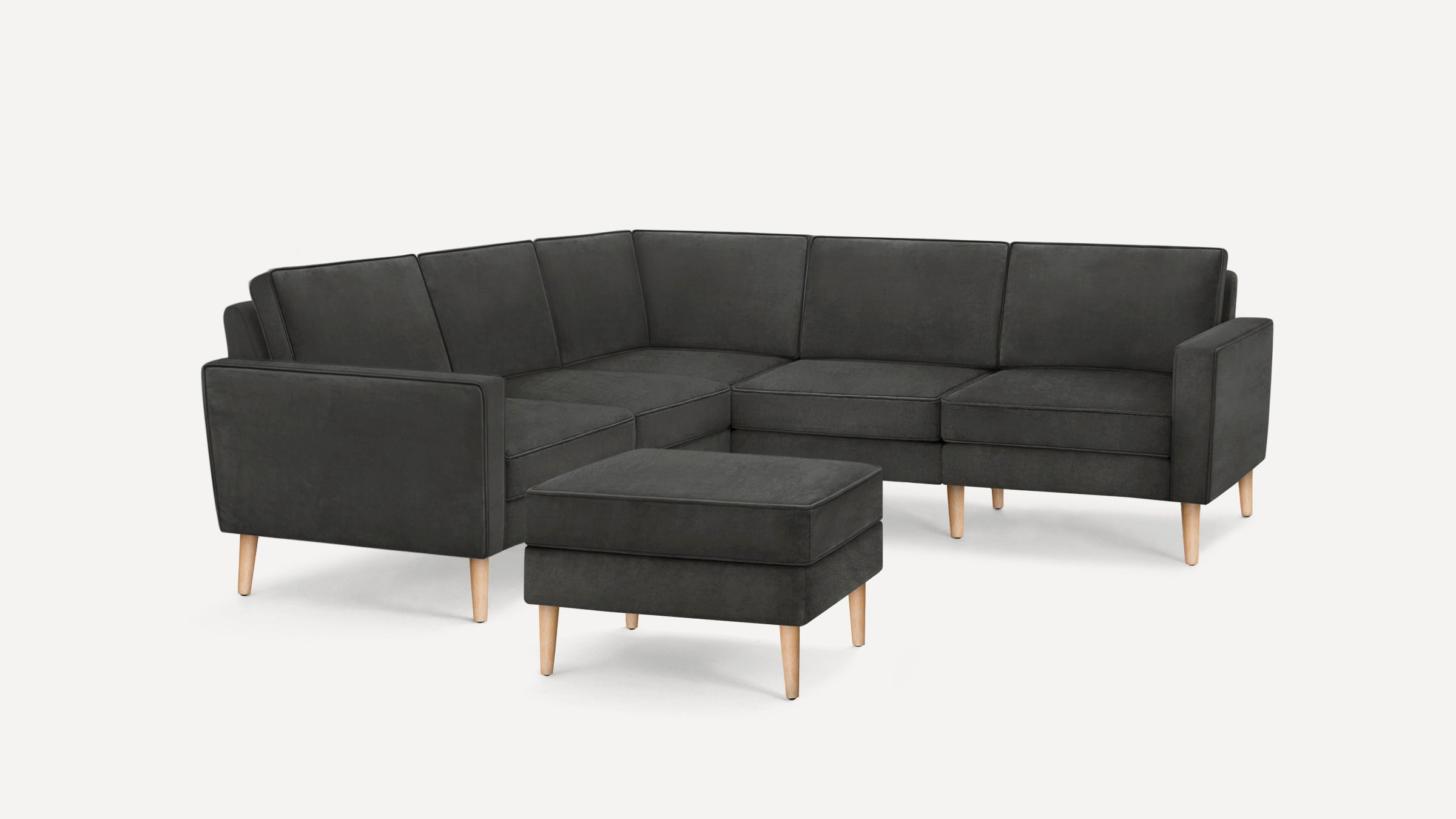 Dark gray L-shaped sectional sofa with matching ottoman, featuring wooden tapered legs and clean modern lines.