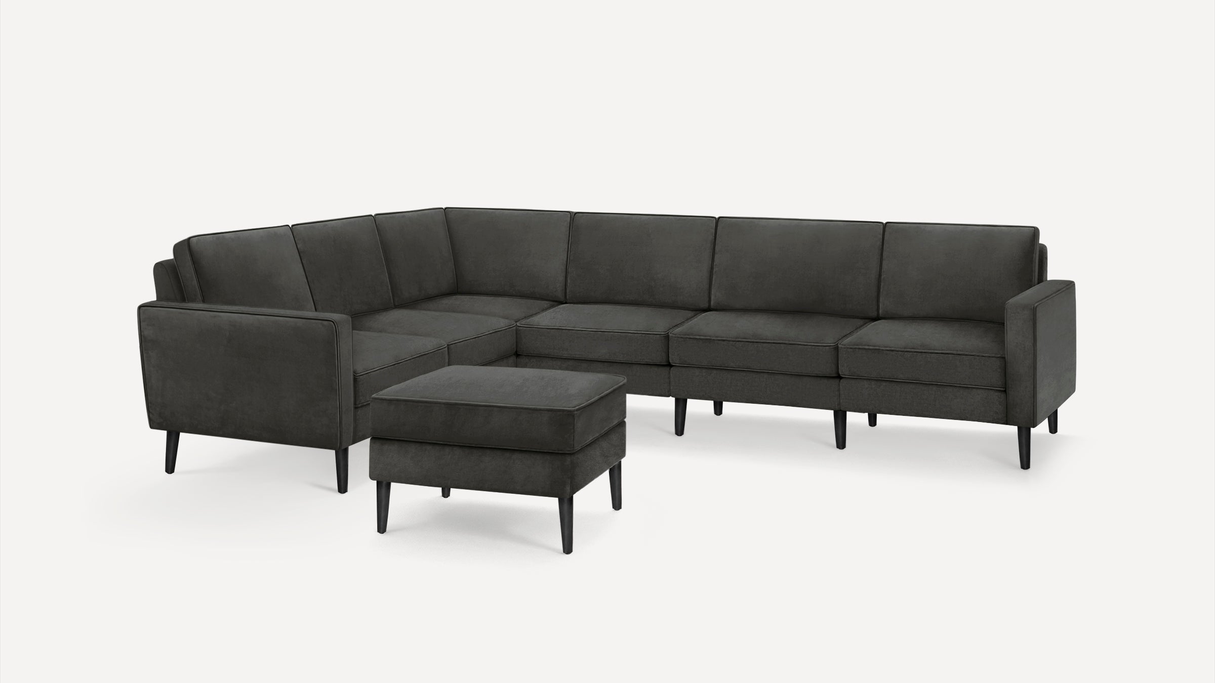 Dark gray modern sectional sofa with clean lines and matching ottoman, featuring tapered black legs and plush cushions.