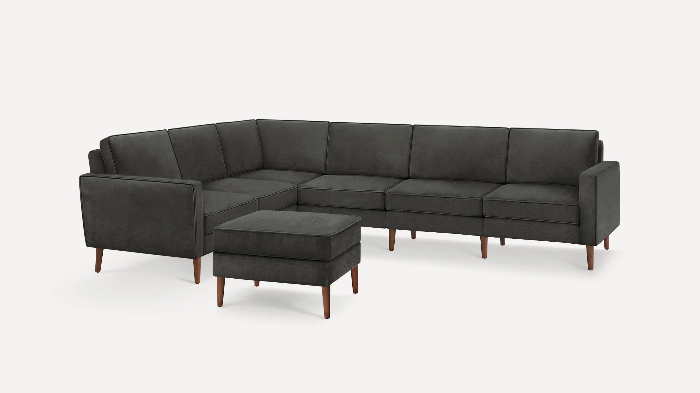 Dark gray L-shaped sectional sofa with wooden legs, accompanied by a matching cushioned ottoman.