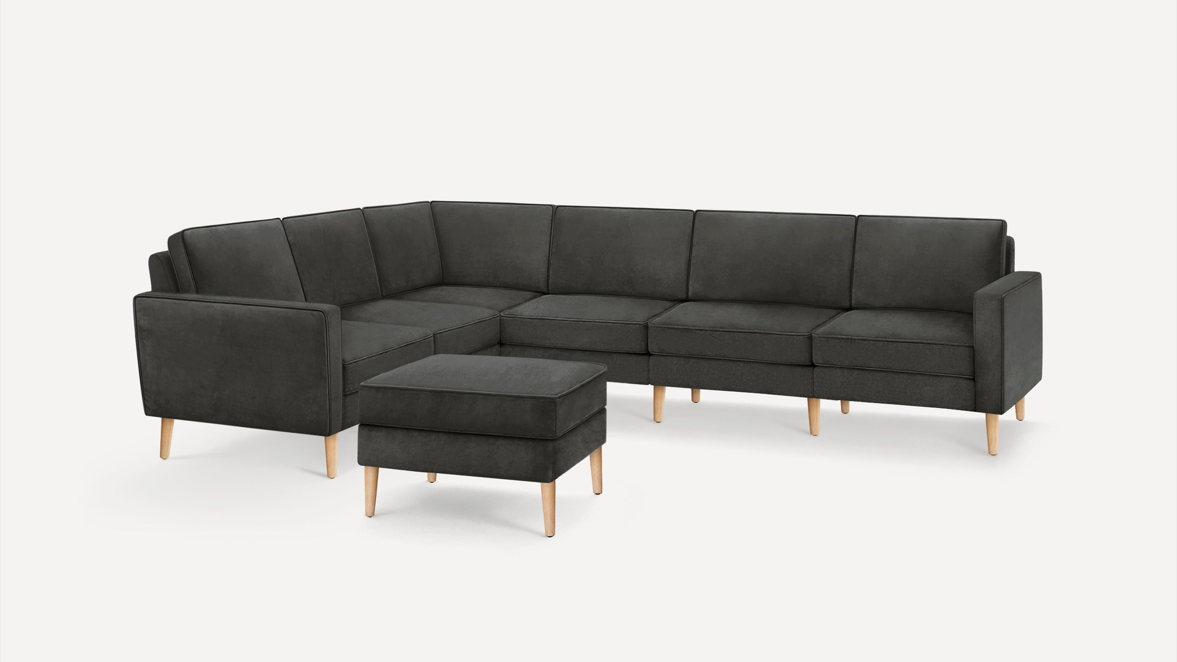 Dark gray modern sectional sofa with clean lines, wooden legs, and a matching square ottoman on a white background.