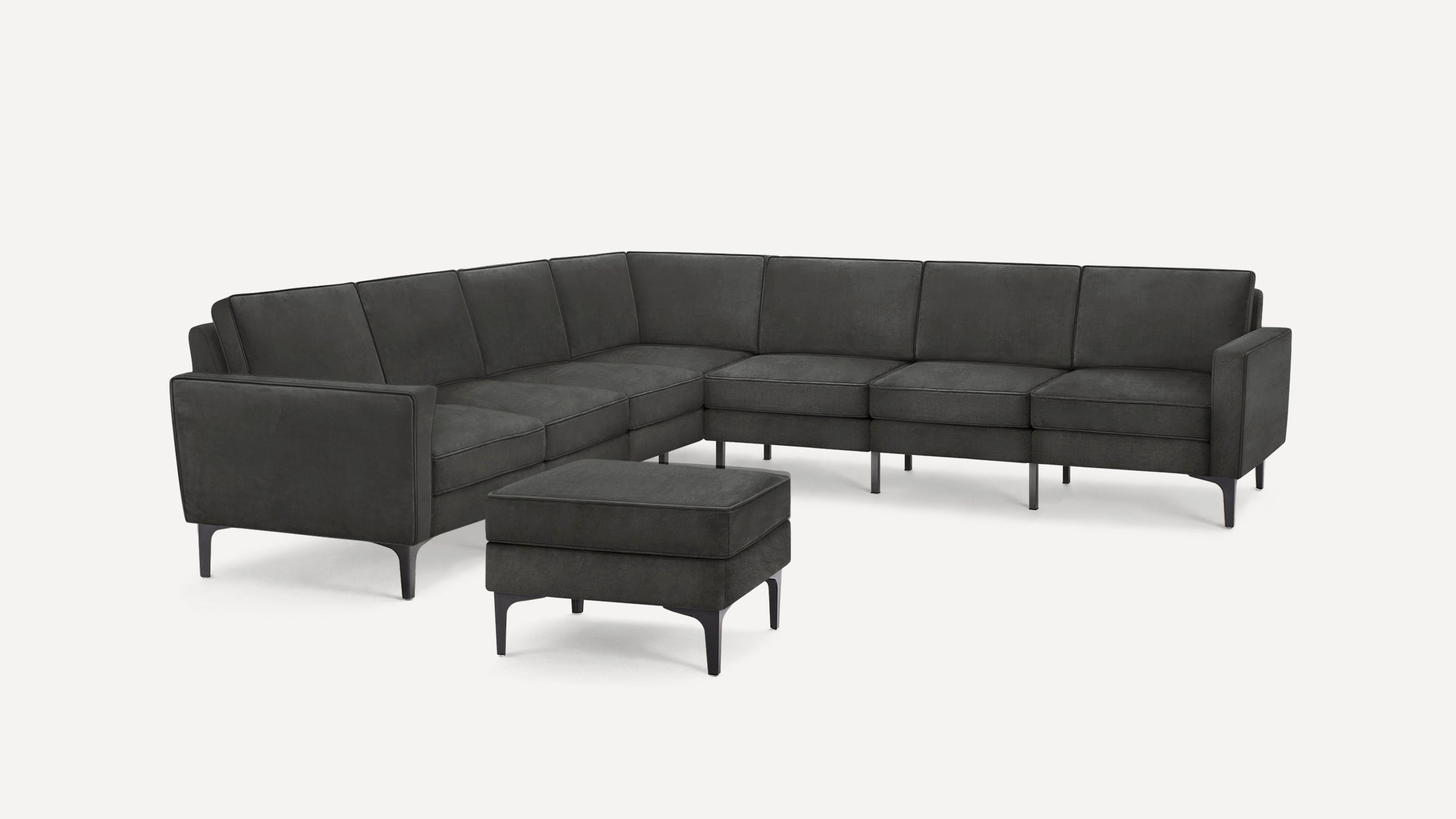 Dark gray L-shaped sectional sofa with sleek metal legs and matching ottoman, featuring modern clean lines.