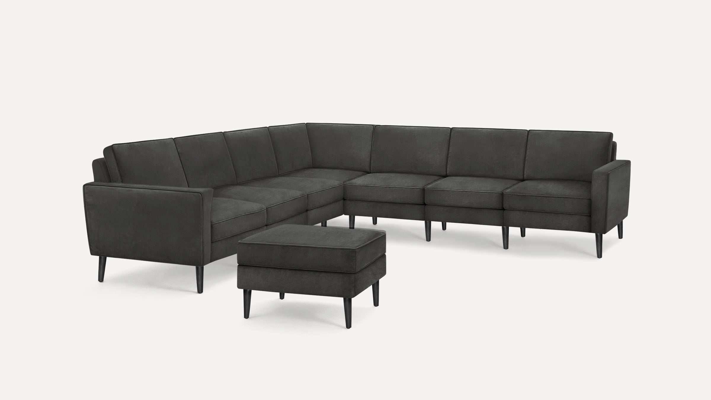 Dark gray modern sectional sofa with clean lines, cushioned seats, and a matching ottoman, featuring slim black legs.