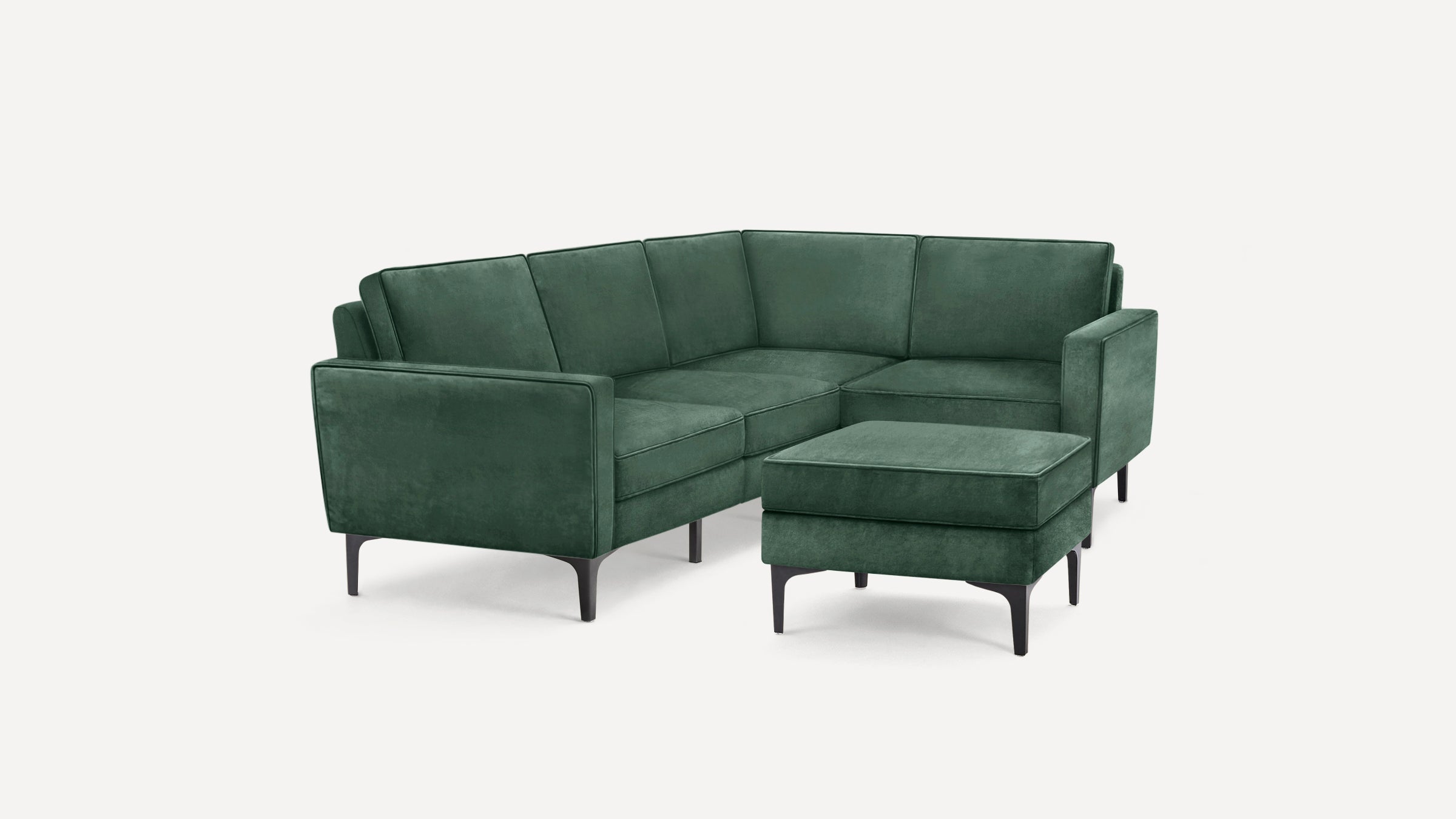 Modern green velvet L-shaped sectional sofa with matching ottoman and sleek black legs on white background.