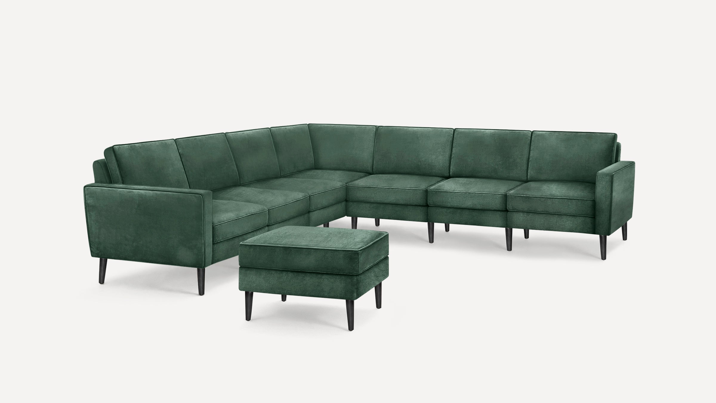 Dark green velvet sectional sofa with matching ottoman, featuring clean lines and black tapered legs on white background.