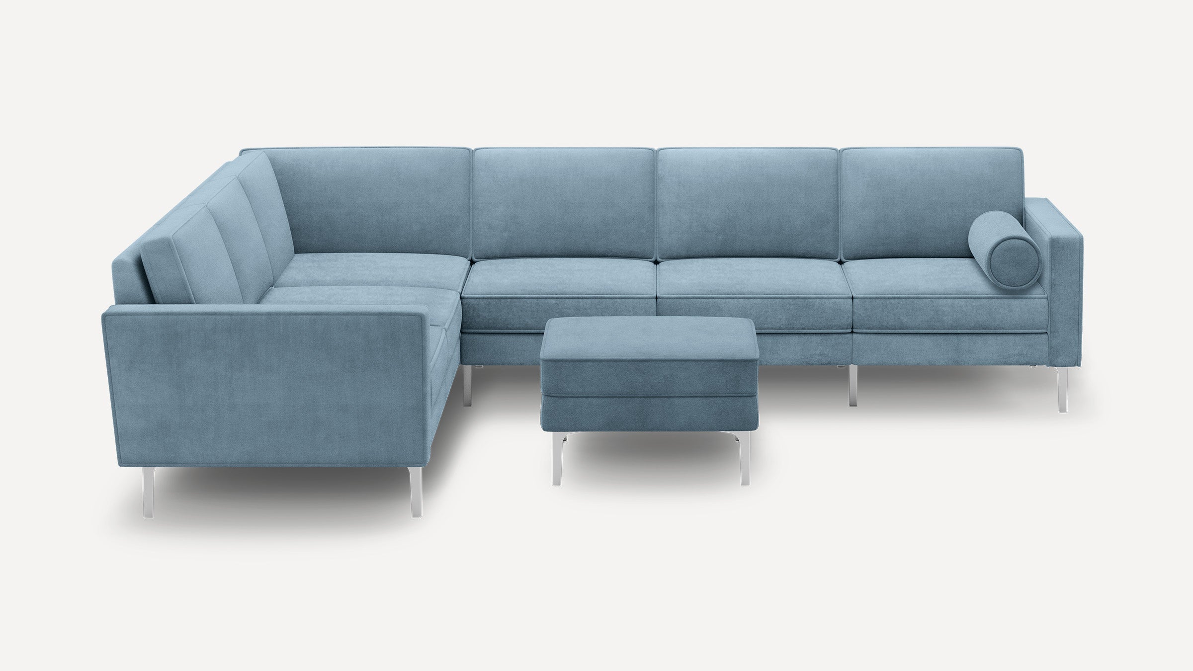 Modern light blue L-shaped sectional sofa with metal legs and matching ottoman, featuring a cylindrical bolster pillow.