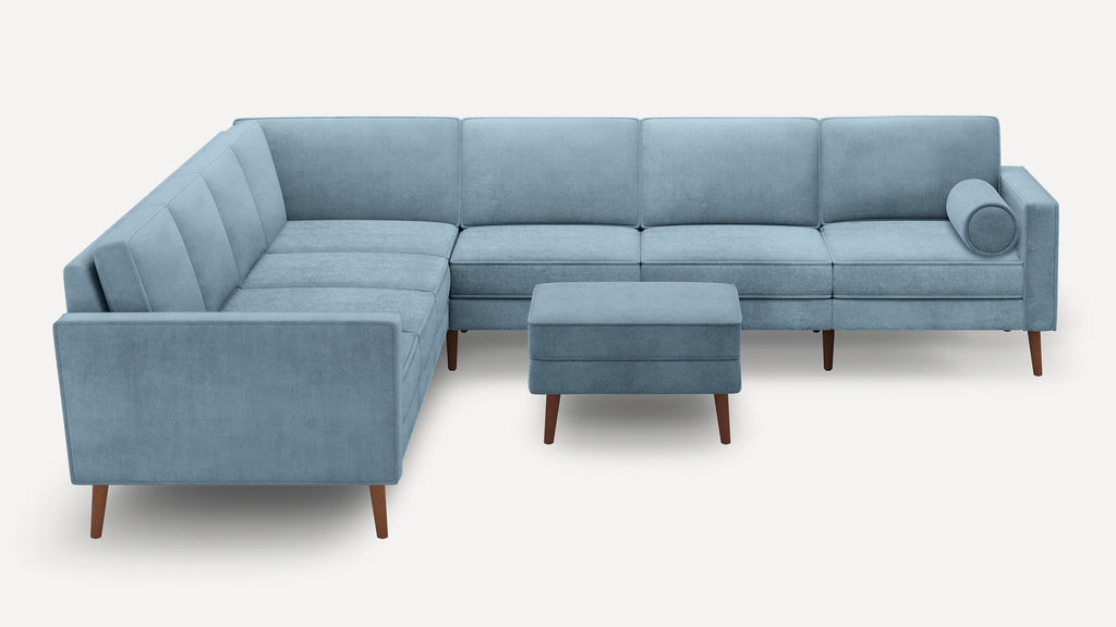 Light blue sectional sofa with wooden legs, includes matching ottoman and cylindrical bolster pillow, minimalist modern design.
