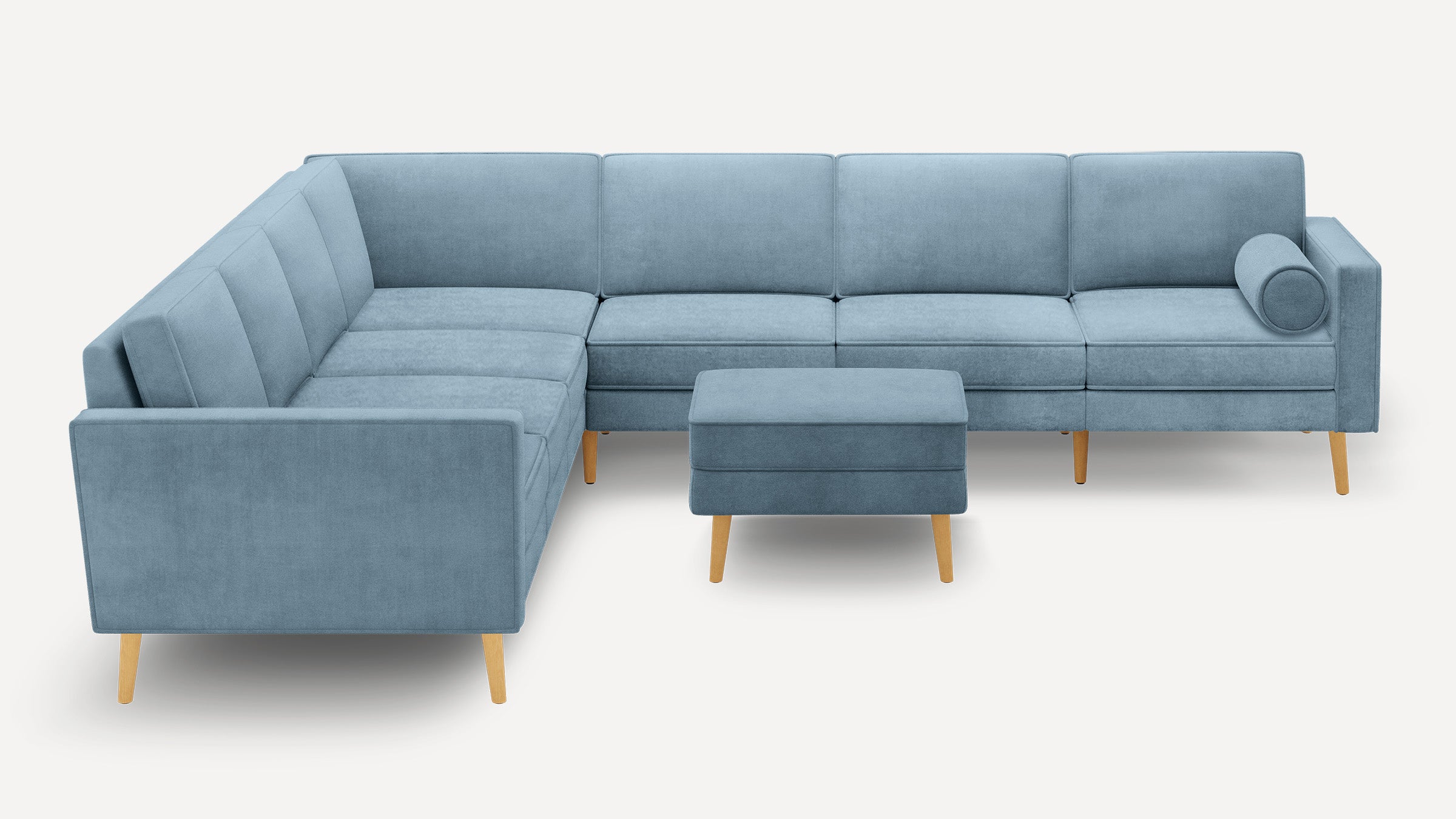 Light blue L-shaped sectional sofa with wooden legs and matching ottoman, featuring clean lines and a cylindrical bolster pillow.