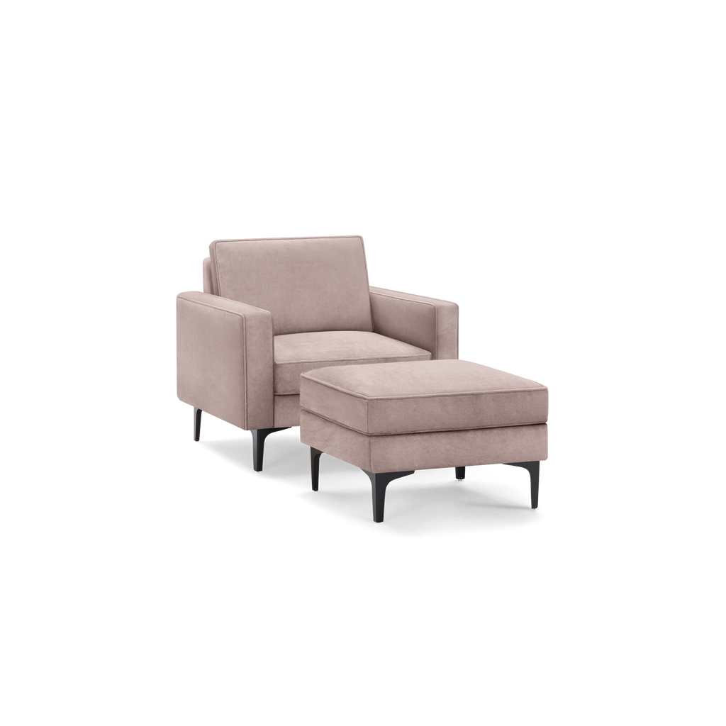 Modern armchair with matching ottoman in soft dusty pink fabric, featuring sleek black tapered legs.