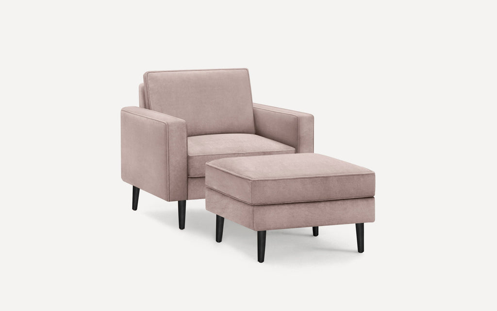 Modern blush pink upholstered armchair with matching ottoman, featuring clean lines and black tapered legs.