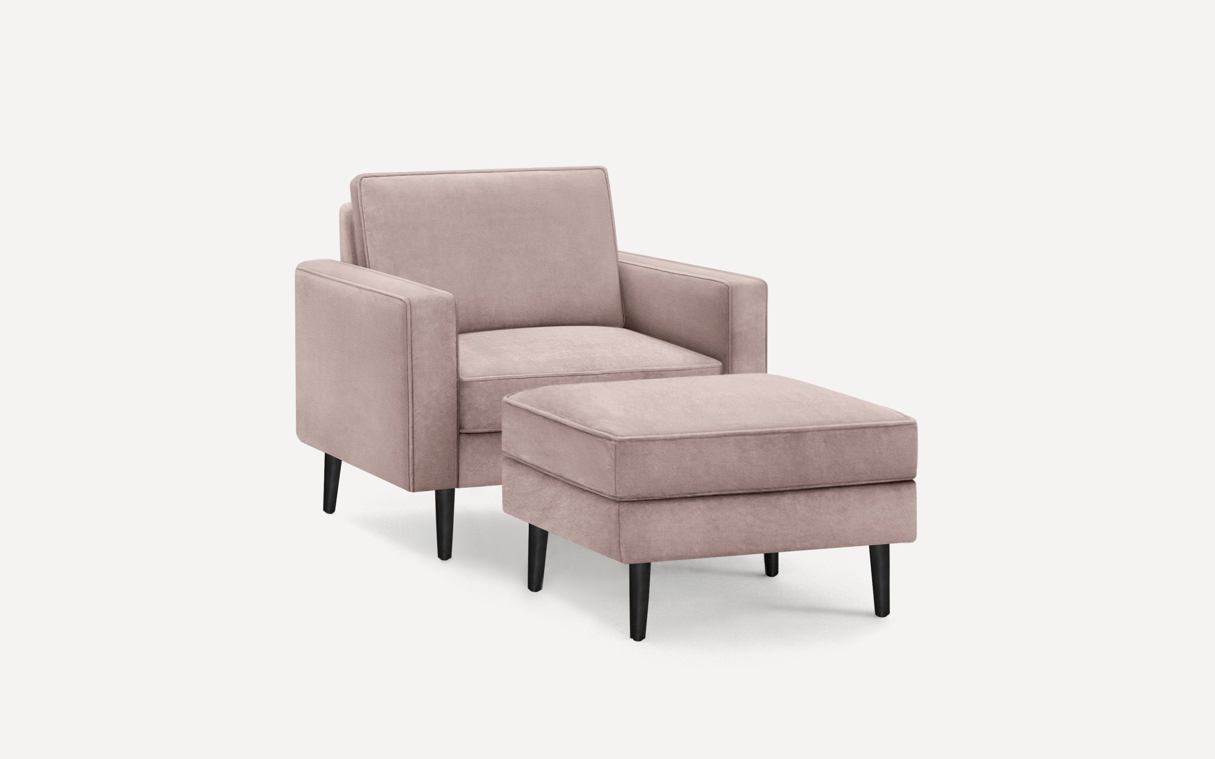 Modern blush pink upholstered armchair with matching ottoman, featuring clean lines and black tapered legs.