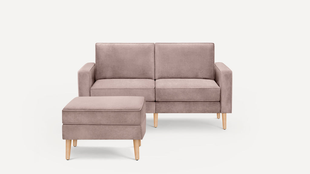 Light mauve two-seater sofa with matching ottoman, both featuring wooden legs and clean, modern design.