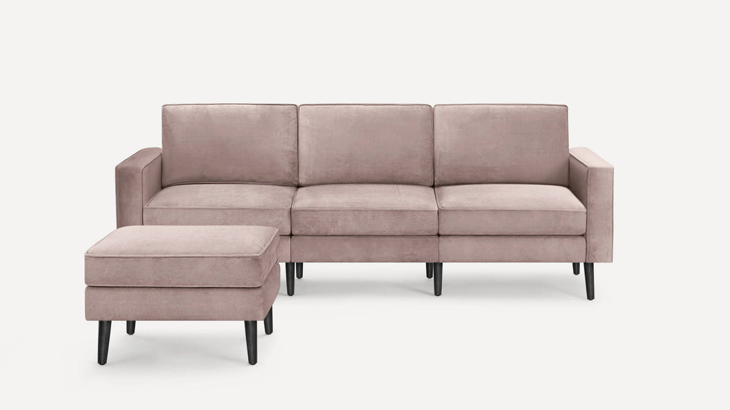 Soft pink upholstered three-seater sofa with matching cushioned ottoman, featuring sleek black tapered legs.