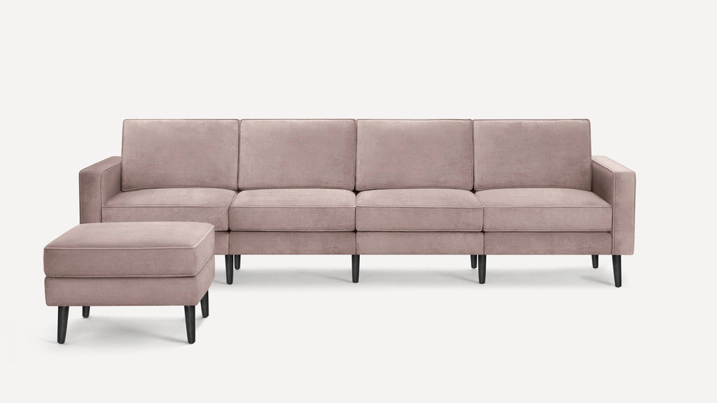 Modern blush pink upholstered four-seater sofa with matching rectangular ottoman, featuring clean lines and black wooden legs.