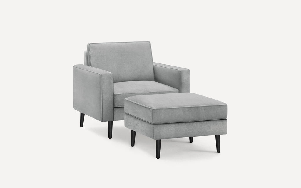 Modern light gray upholstered armchair with matching ottoman, both featuring black tapered wooden legs.