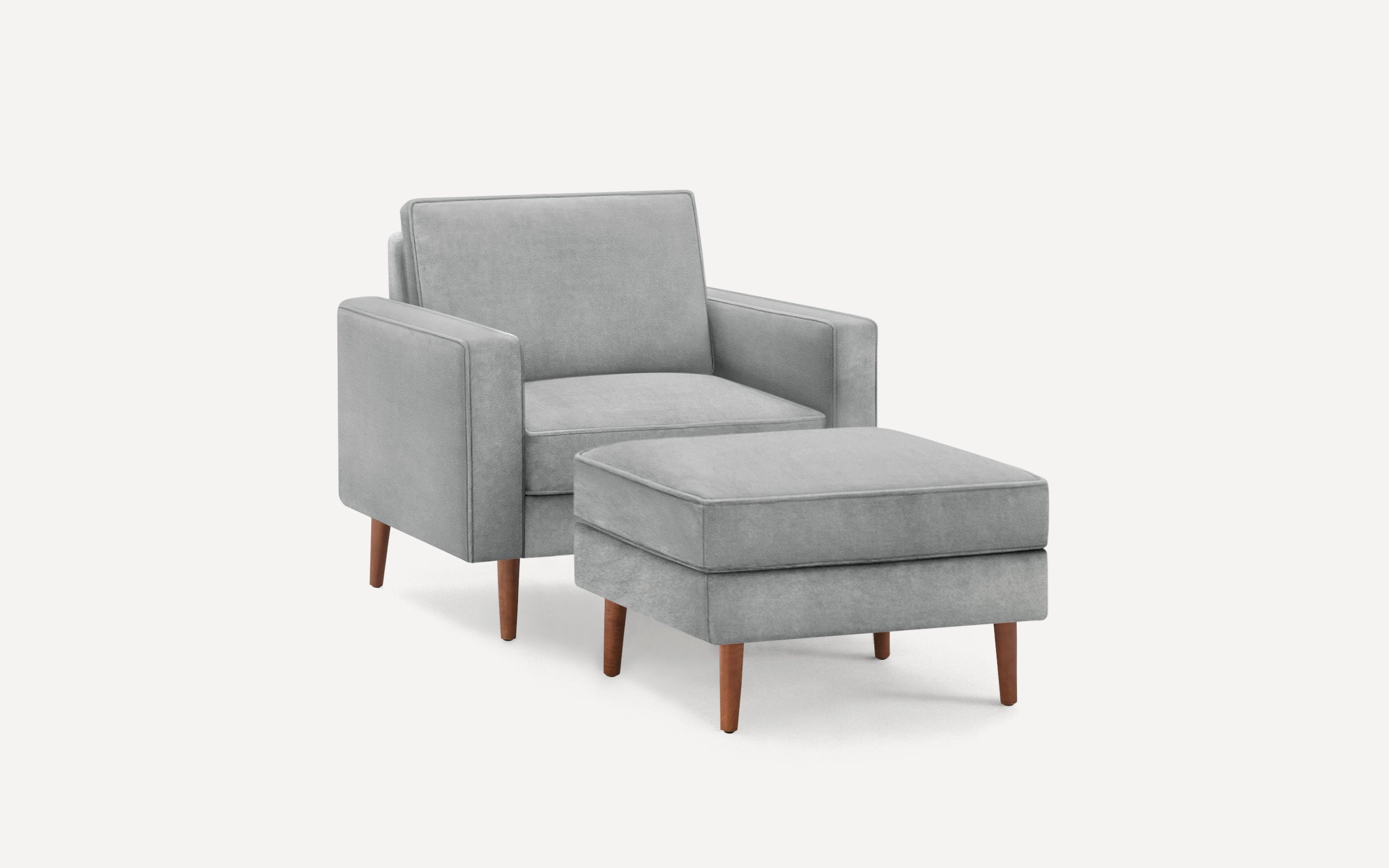 Light gray upholstered armchair with matching ottoman, both featuring wooden tapered legs and clean modern lines.